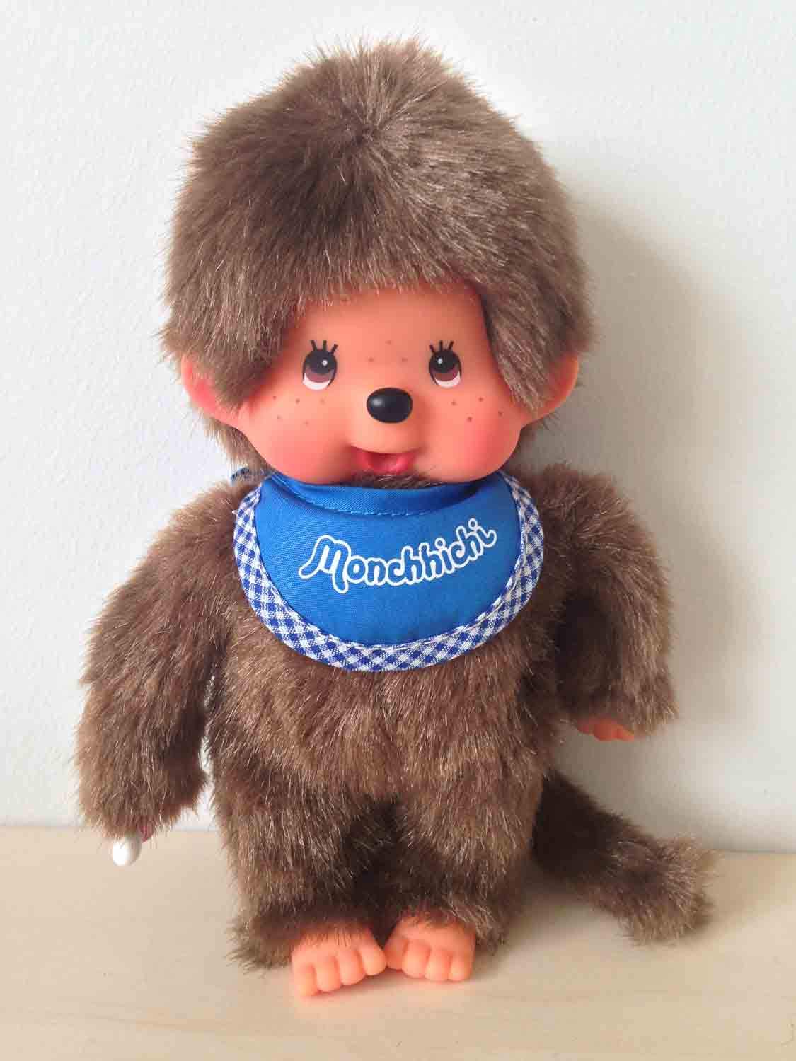 Sekiguchi 255040 - Original Monchhichi Junge, Plüschtier mit blauem Lätzchen und Zöpfen mit Schleifen, ca. 20 cm großes Kuscheltier aus braunem Plüsch, Braun - Image 7
